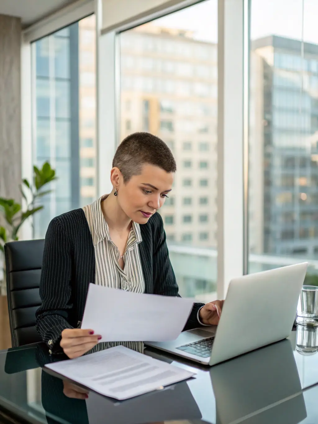 A Canadian small business owner reviewing financial statements with a focused expression, highlighting the importance of cash flow management. The setting is a modern, bright office space.